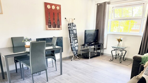 Moderni olohuone, jossa on ruokailutila, televisio ja ikkuna, jossa on verhot.