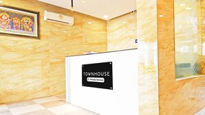 Vastaanottotiski, jossa on kyltti, jossa lukee: ”TOWNHOUSE – tarjoamme lisäpalveluita”.
