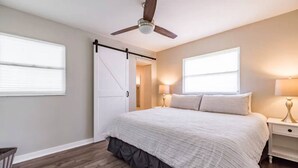 A bedroom with a bed, a ceiling fan, a sliding door, two bedside lamps, and a window. - Beautiful Tampa Pool/Hot Tub Home-Spacious Yard (Tampa)