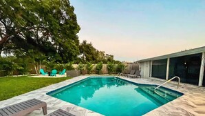 A rectangular swimming pool with a clear blue water surface, surrounded by a patterned stone deck. - Beautiful Tampa Pool/Hot Tub Home-Spacious Yard (Tampa)