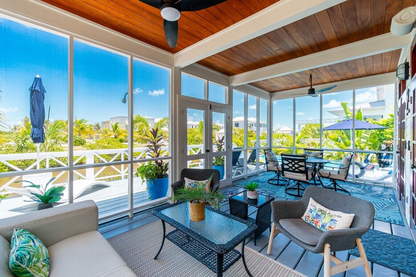 A sunroom with large windows, a ceiling fan, and a view of a pool and greenery.