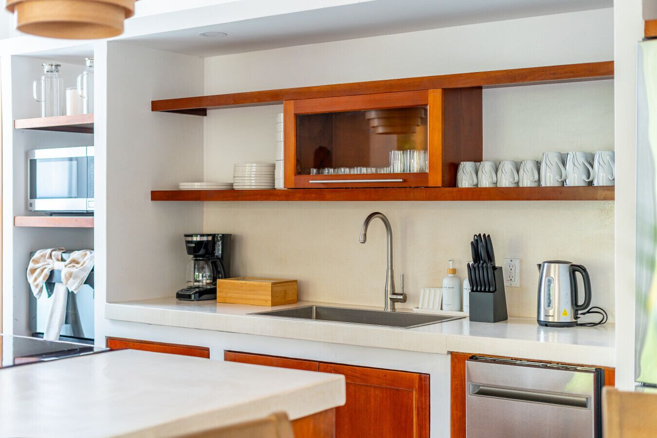 Una cucina moderna con lavello in acciaio inossidabile, mobili in legno e macchina per il caffè.
