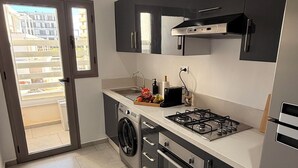 Une cuisine moderne équipée d’une cuisinière à gaz, d’un four, d’un lave-linge et d’une grande fenêtre.