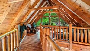 A wooden attic room with a wooden railing, a sofa, and a small table. - 1/2 Mile to Parkway*3 BR*Hot Tub*Games*Comm. Pool (Pigeon Forge)