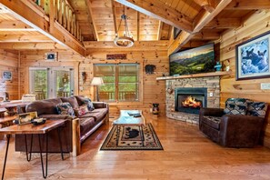 Ein rustikales Holzhaus-Interieur mit Kamin, Holzwänden, einer Couch und einem Essbereich.