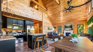 A modern log cabin interior with a kitchen, dining area, and living room. - New! Indoor Pool w/Hot Tub*Putting Green*Pets! (Sevierville)