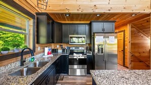 A modern kitchen with granite countertops, stainless steel appliances, and wooden cabinetry. - New! Indoor Pool w/Hot Tub*Putting Green*Pets! (Sevierville)