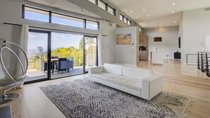 A modern living room with a white sofa, a large rug, and a dining area with a table and chairs. - The Hollywood Hills Executive - Incredible Sunsets- Next to Studios! (Los Angeles)