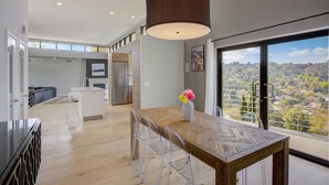 A modern kitchen with a wooden dining table, clear chairs, and a large pendant light. - The Hollywood Hills Executive - Incredible Sunsets- Next to Studios! (Los Angeles)