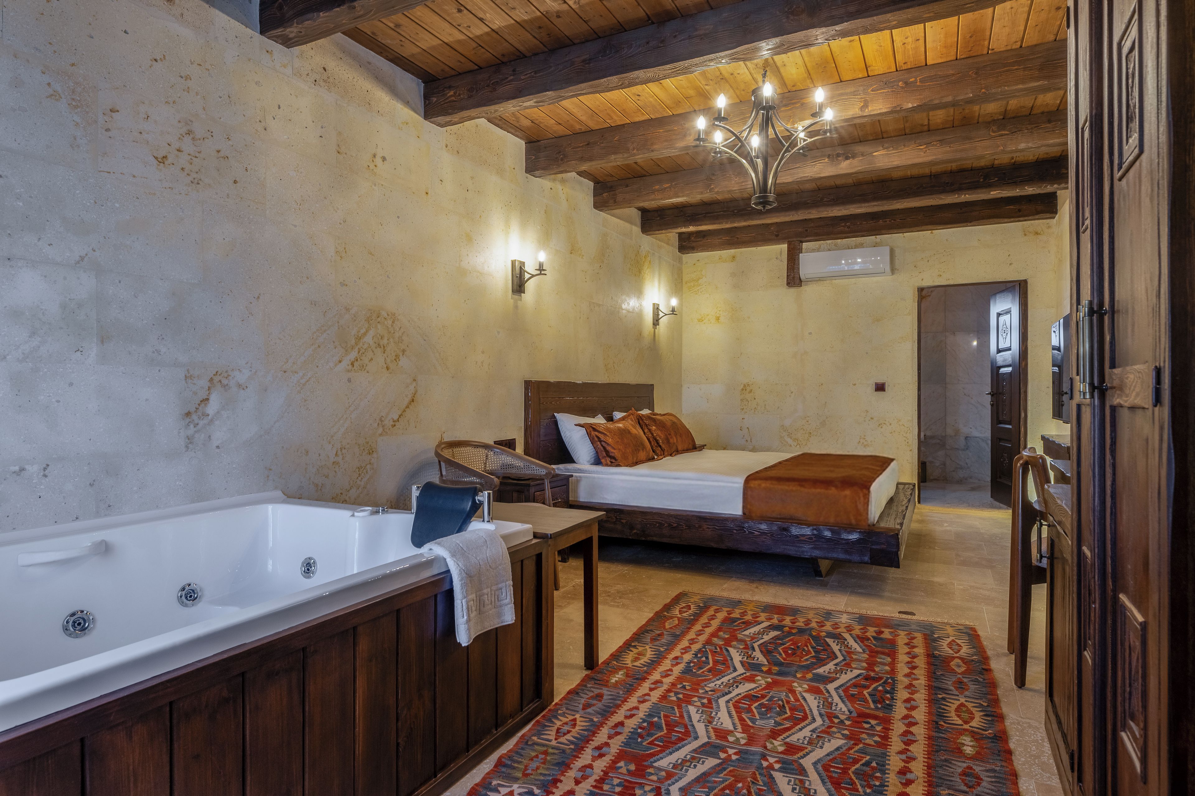 Un baño rústico con una bañera, un banco de madera y una cama con un tapete estampado.