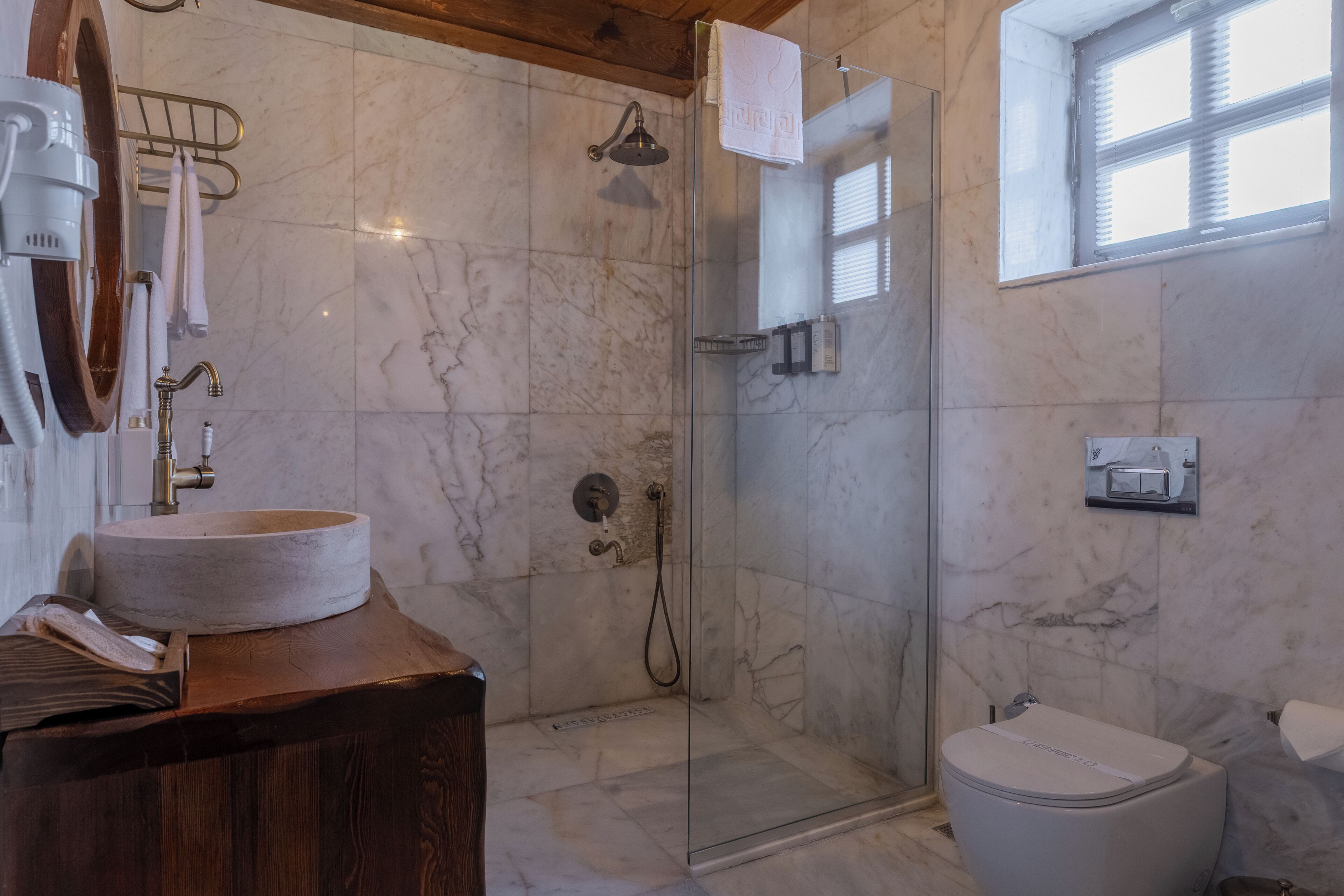 Un baño con lavamanos de mármol, cabina de ducha de vidrio y un inodoro.
