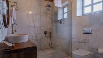 Un baño con lavamanos de mármol, cabina de ducha de vidrio y un inodoro.