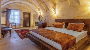 A bedroom with a large bed, wooden headboard, a desk, and a chair. - Noble Blue Cappadocia  (Urgup)