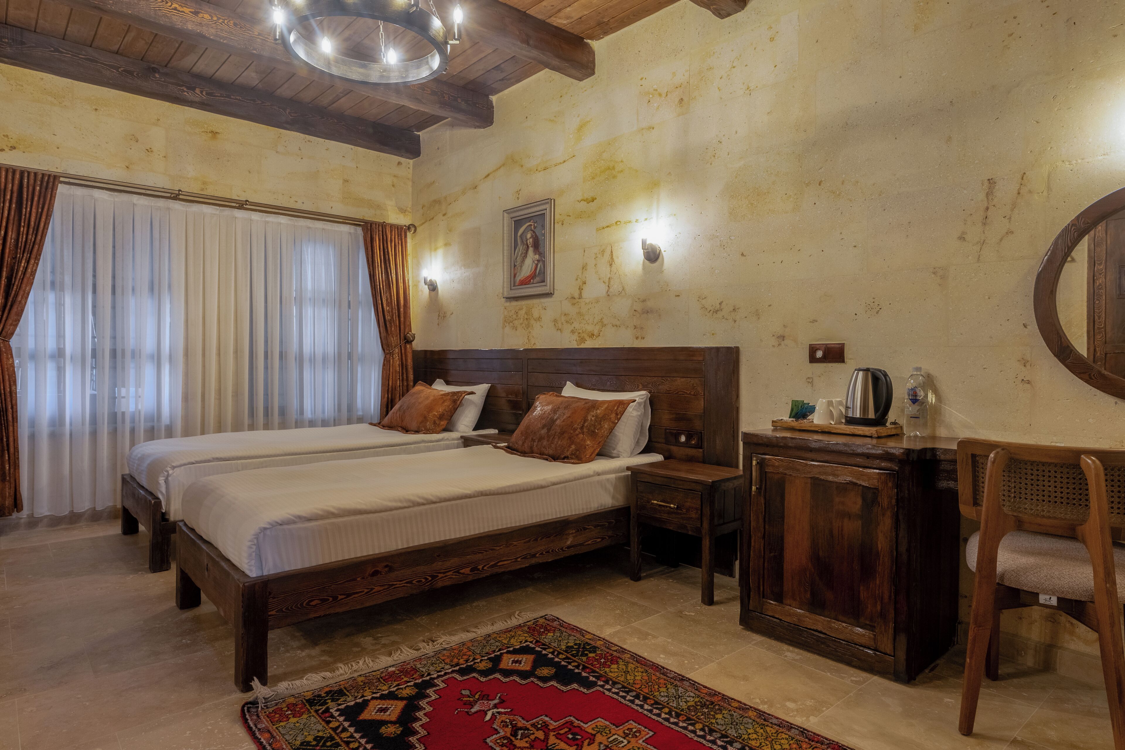 A bedroom with a large bed, wooden headboard, bedside tables, a desk, and a chair.