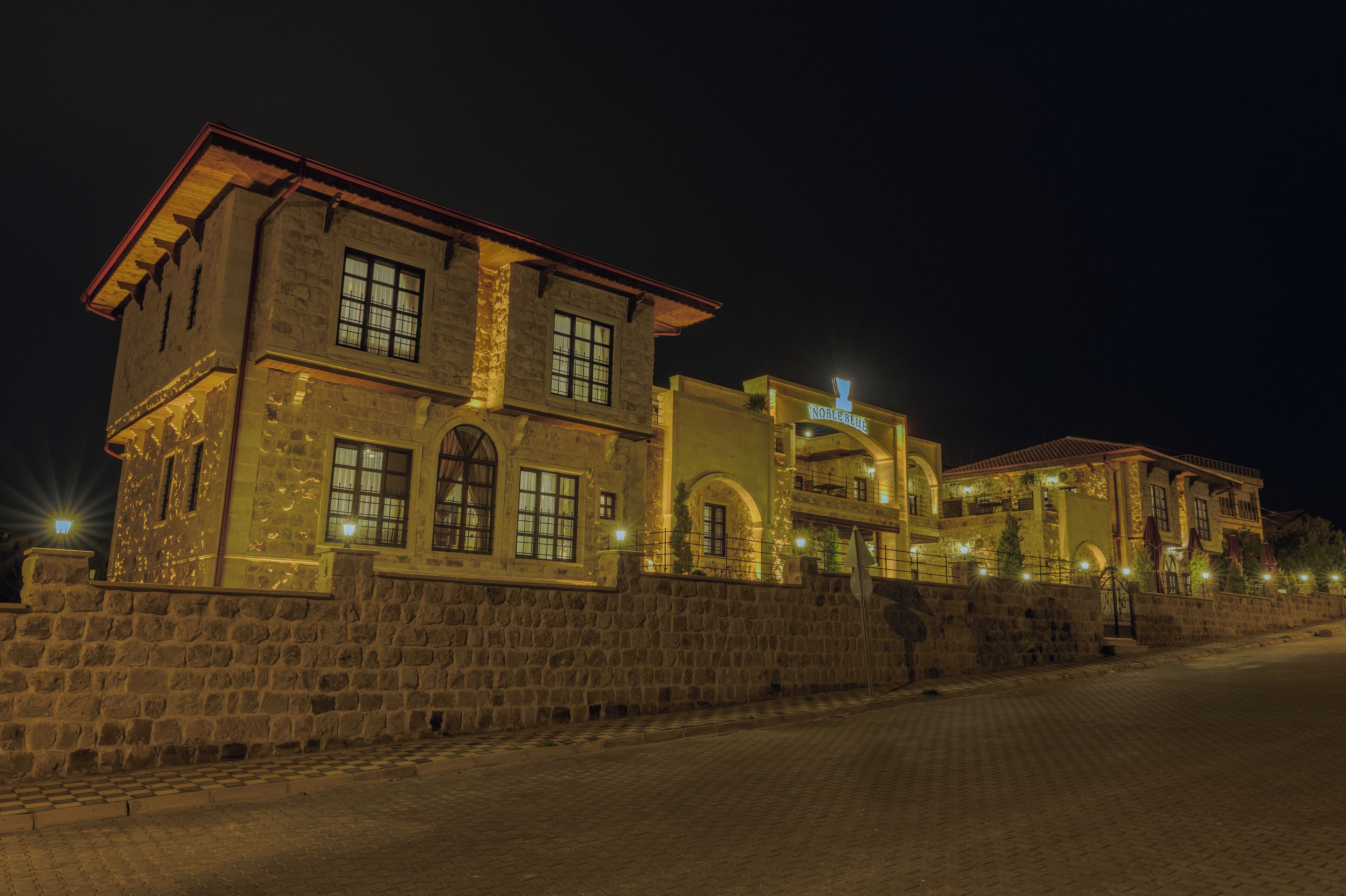A historic building with multiple stories, stone walls, and illuminated windows.