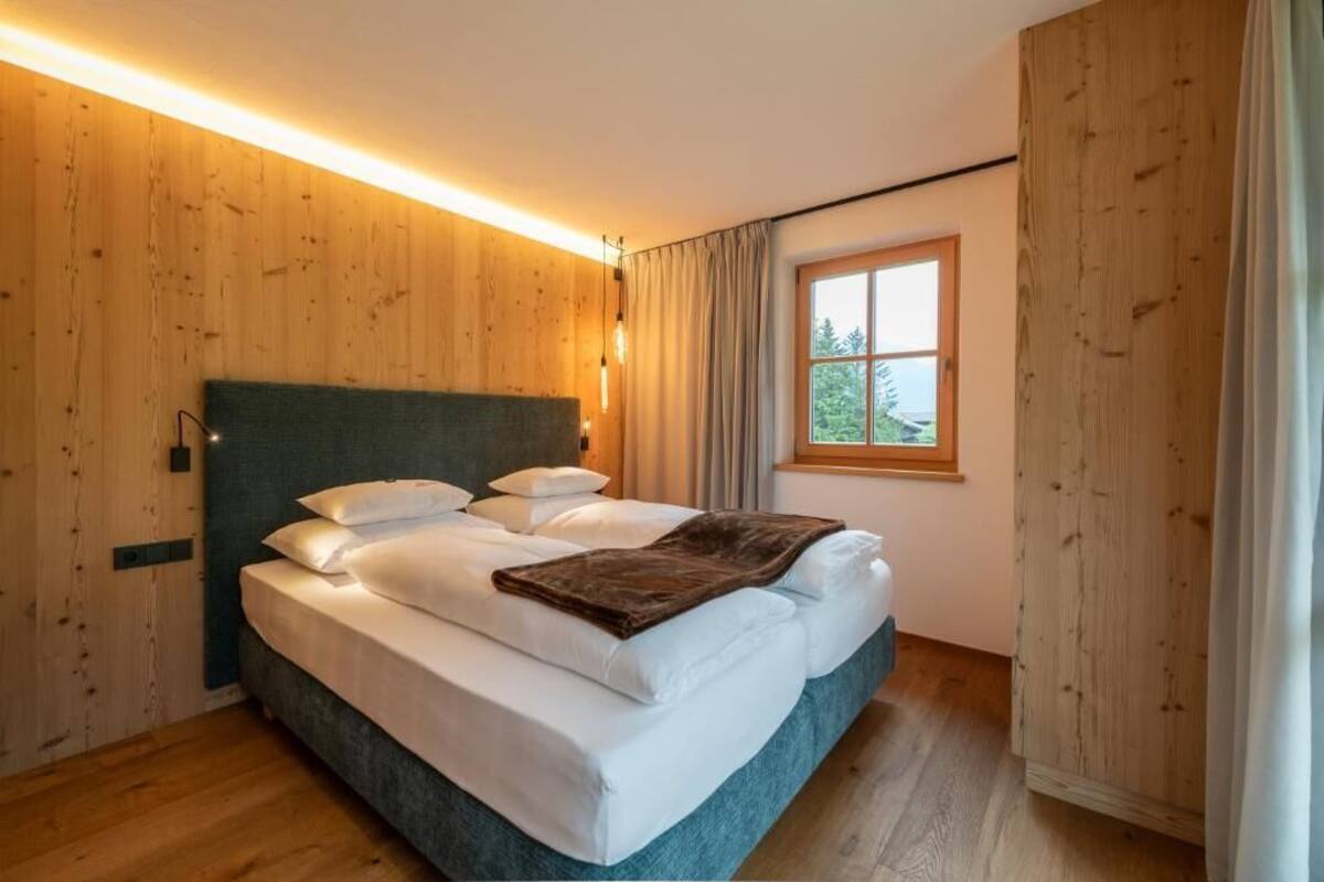 Ein Schlafzimmer mit Holzwänden, einem Bett mit weißen Leinen, einem Fenster mit Ausblick und einem Holzboden.