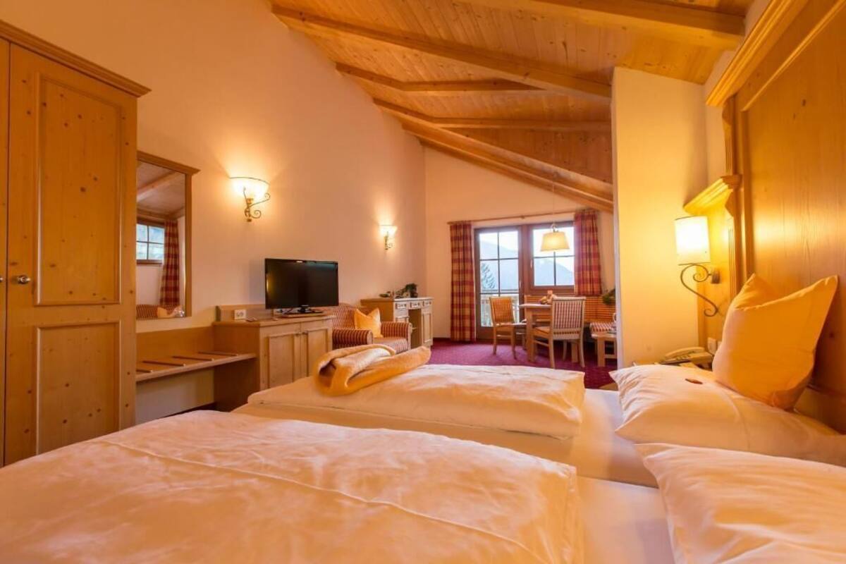 Ein Hotelzimmer mit Holzboden, einem Bett, einem Schreibtisch, einem Stuhl und einem Fernseher.