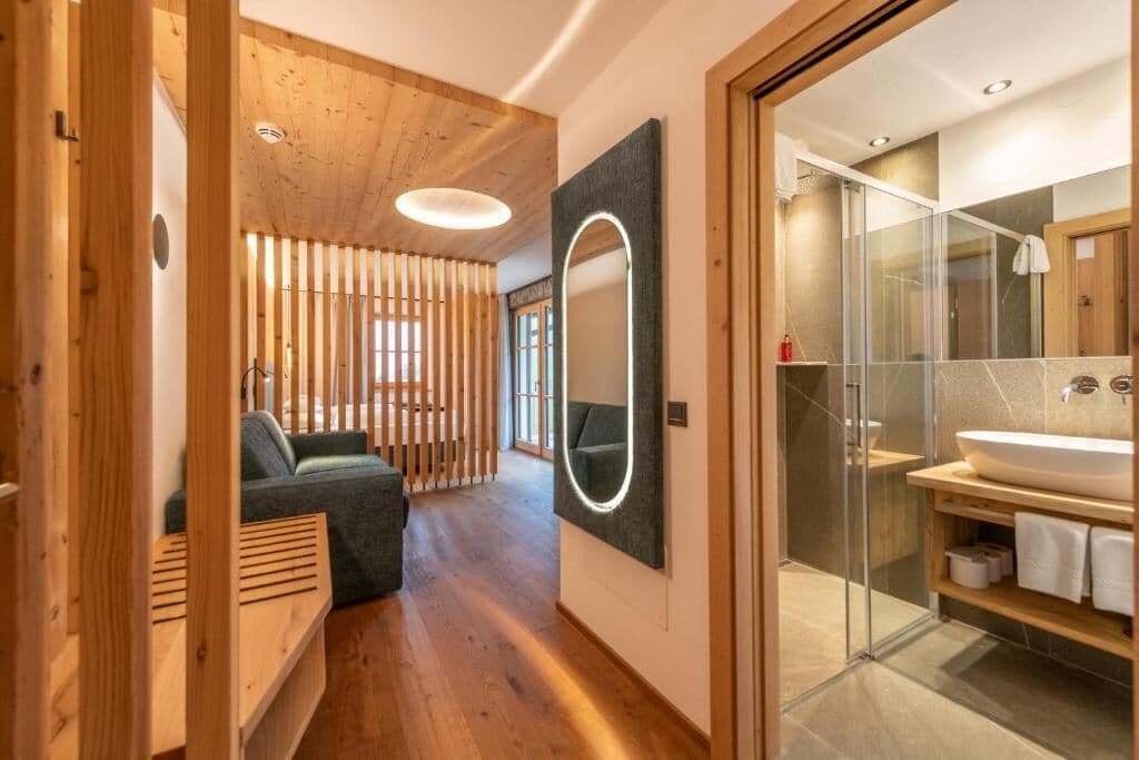 Un baño moderno con cabina de ducha de vidrio, un espejo grande y suelo de madera.