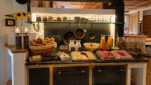 Ein Buffet mit verschiedenen Speisen, darunter Fleisch, Käse und Beilagen.