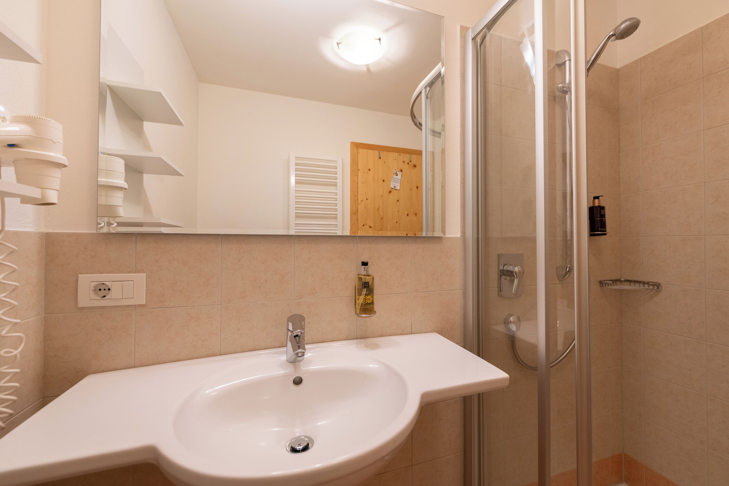 Une salle de bain avec un lavabo, un miroir, une douche et une porte en bois.
