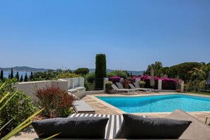 Ein Poolbereich mit Liegestühlen, einem kleinen Pool und Meerblick.