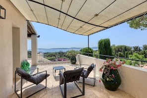Ein Balkon mit Meerblick, einem Tisch, zwei Stühlen und einem großen Blumentopf.
