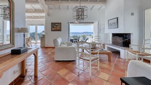 Un salón amplio con chimenea, televisor y vistas al exterior.