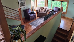 A spacious living area with a high ceiling, a staircase, and large windows. - Heron's Nest - Elegant King Master with custom woodwork, lofts and stained glass (Eugene)