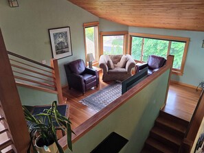 A spacious living area with a high ceiling, a staircase, and large windows. - Heron's Nest - Elegant King Master with custom woodwork, lofts and stained glass (Eugene)