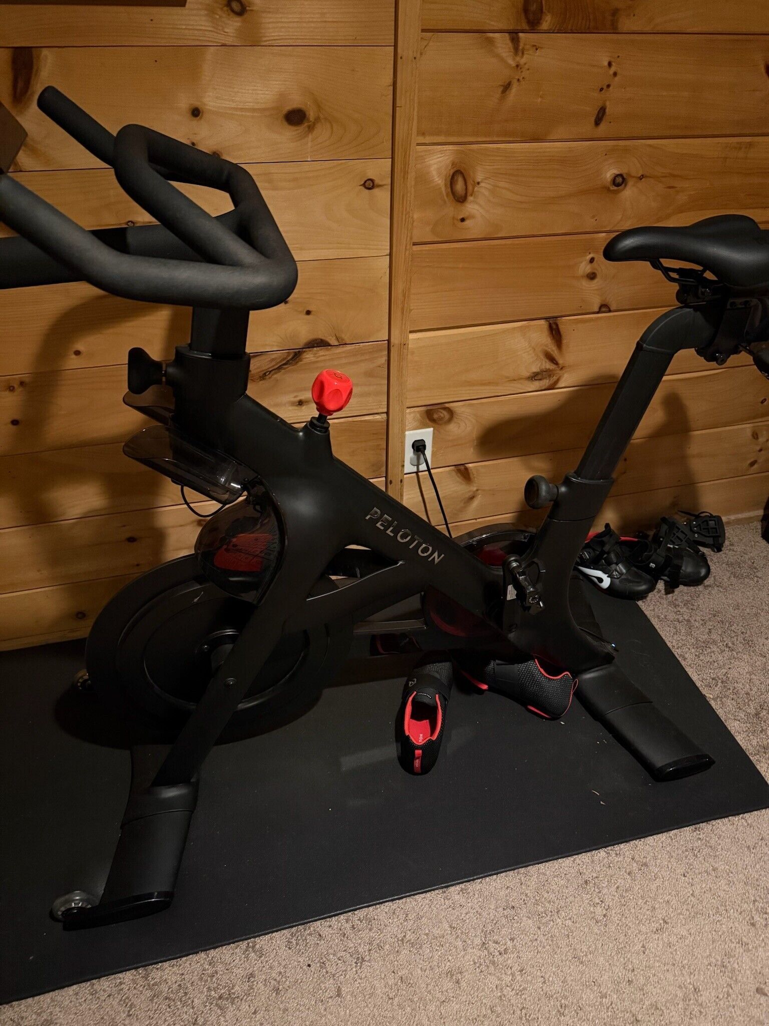 A stationary exercise bike with a red knob, a black seat, and a control panel.