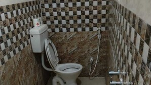 Een kleine badkamer met toilet, bidet en prullenbak.