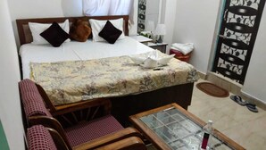 Een slaapkamer met een bed, een bank, een tafel met glazen blad en een stoel.