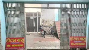 Een hotelentree met metalen poorten, een motor en een fiets die er geparkeerd staan.