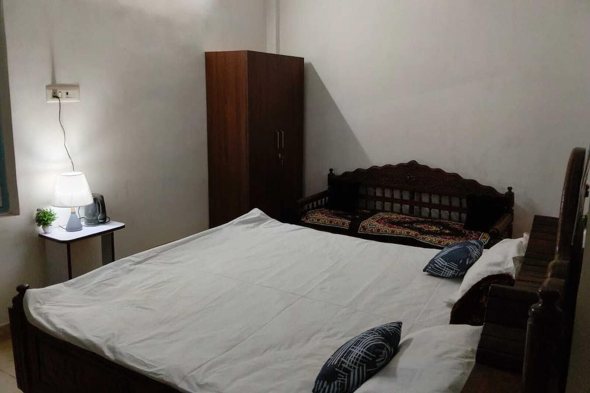 Ein Schlafzimmer mit Bett, Nachttisch mit Lampe, Kleiderschrank und Fenster.