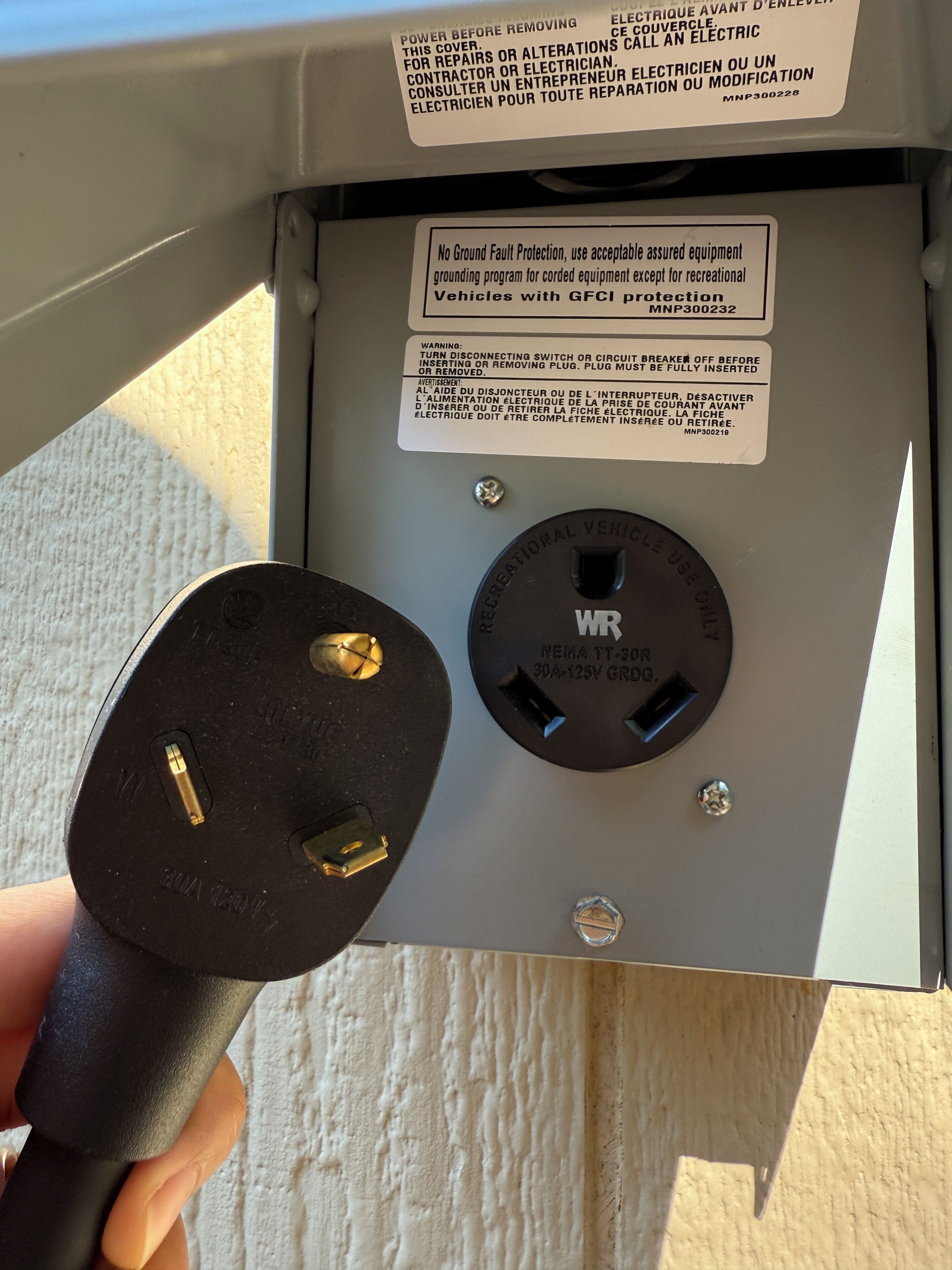 Un cuadro eléctrico con etiquetas de advertencia y un enchufe.