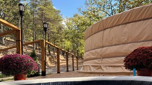 A swimming pool with a wooden deck, surrounded by trees and covered with a beige tarp.