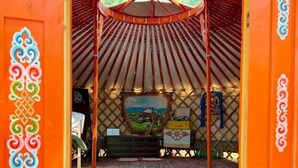 Une yourte traditionnelle avec un plafond en bois, une peinture centrale et une petite table sur laquelle sont posés divers objets.