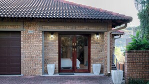 A brick building with a tiled roof, a garage door, and two large planters.