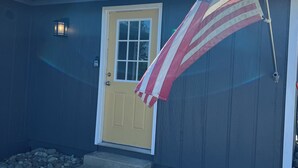 A building with a yellow door, an American flag, and a stone-paved entrance. - Holly House in Sequim (Sequim)