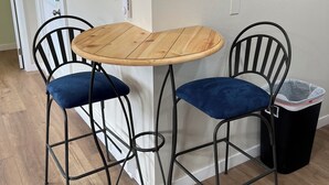 A small dining area with a round wooden table and two black metal chairs with blue cushions. - Holly House in Sequim (Sequim)