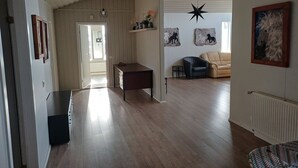 Ein geräumiger Wohnbereich mit Holzboden, einem Schreibtisch, einem Sessel, einer Couch und Kunstwerken an den Wänden.