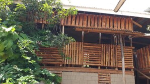 Une structure en bois dotée d’un balcon, entourée d’un feuillage dense.