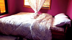 Un lit avec une couvre-lit à motifs, une table de chevet et une fenêtre avec des rideaux.
