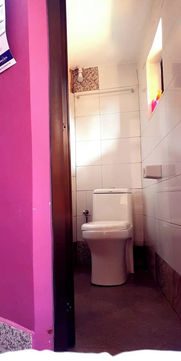 A small bathroom with a toilet, a towel rack, and a shower area. - CAVEJESUS PARK LODGE (Himo)