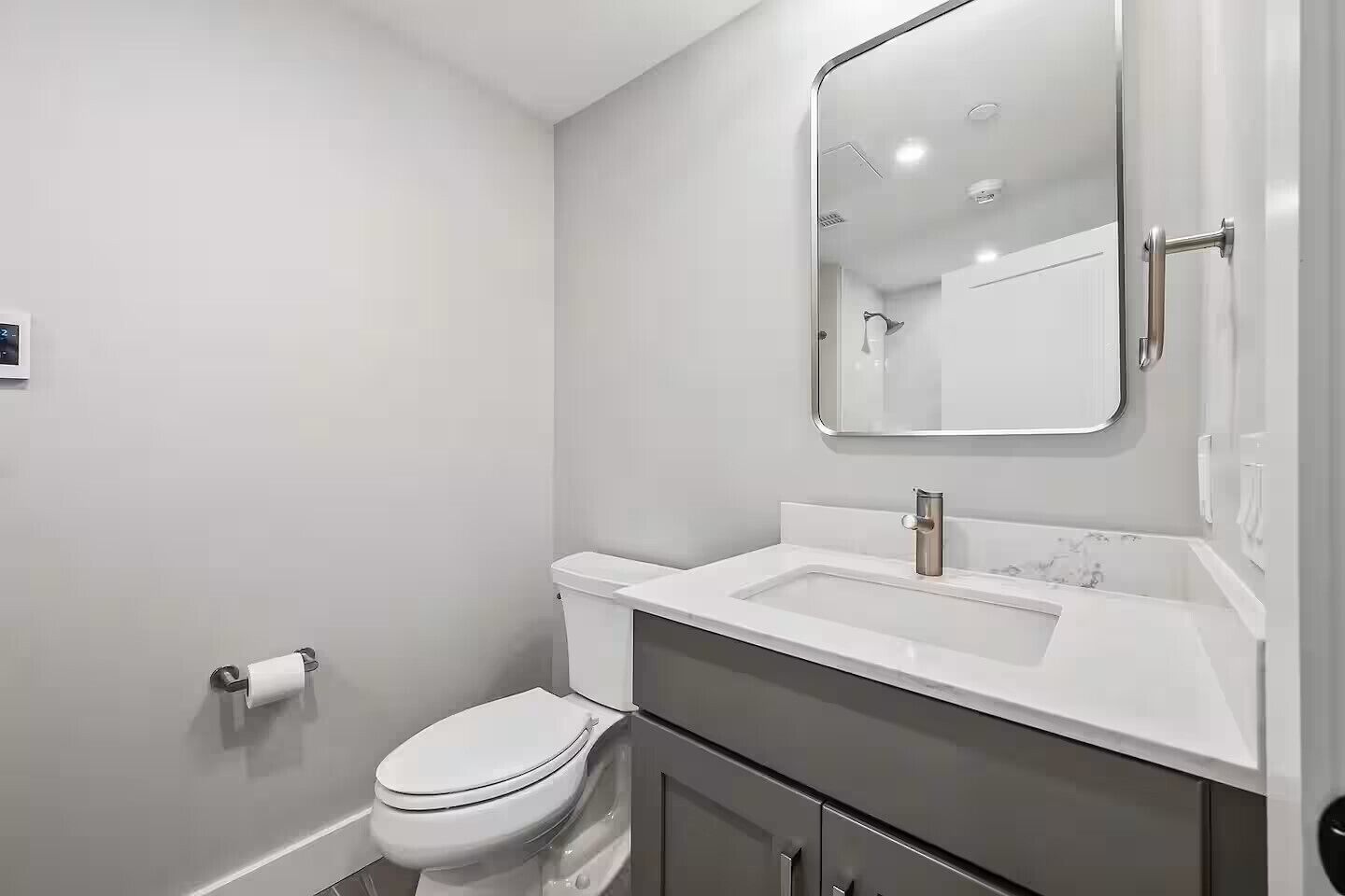 A modern bathroom with a toilet, sink, and mirror.