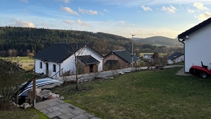Ländliche Landschaft mit Häusern, einem befestigten Weg und einem Traktor.