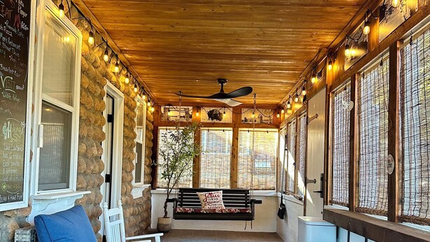 A covered patio with wicker furniture, a ceiling fan, and stone walls. - Lone Oak Cottage Fully restored cabin with 5 beds & walk in shower (Medicine Park)