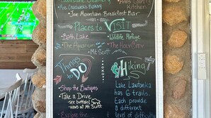 A chalkboard sign with various local attractions and activities listed, such as restaurants, hiking trails, and a wildlife refuge. - Lone Oak Cottage Fully restored cabin with 5 beds & walk in shower (Medicine Park)