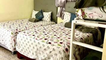 A bedroom with two beds, a ceiling fan, an air conditioning unit, and a shelf with folded blankets.