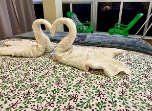 A bed with a floral bedspread and two swan-shaped towels. - Hotel María Bonita Higuey Apartment 7 (Higuey)